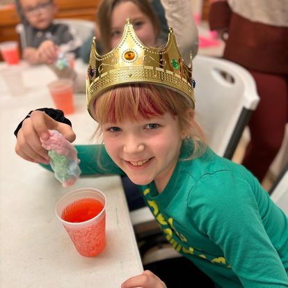 girl in crown dipping cotton candy in drink