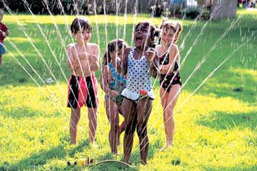 children enjoying sprinkler at Summer camp