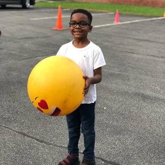boy holding big ball in parking lot