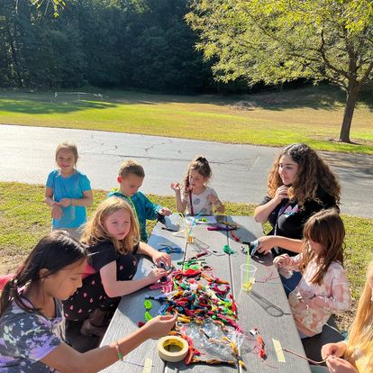 students making bracelets outside at table