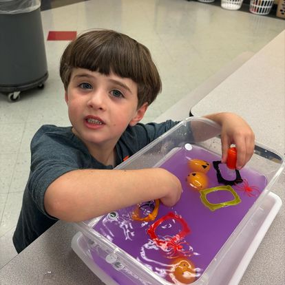 student playing with toys in purple water