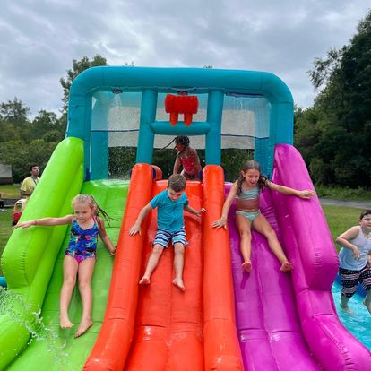 3 kids sliding down inflatable water slide